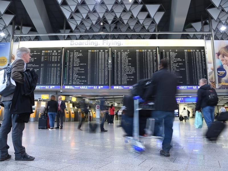 Passagiere vor Anzeigetafel auf Flughafen in Frankfurt. Foto: Boris Roessler/Archiv