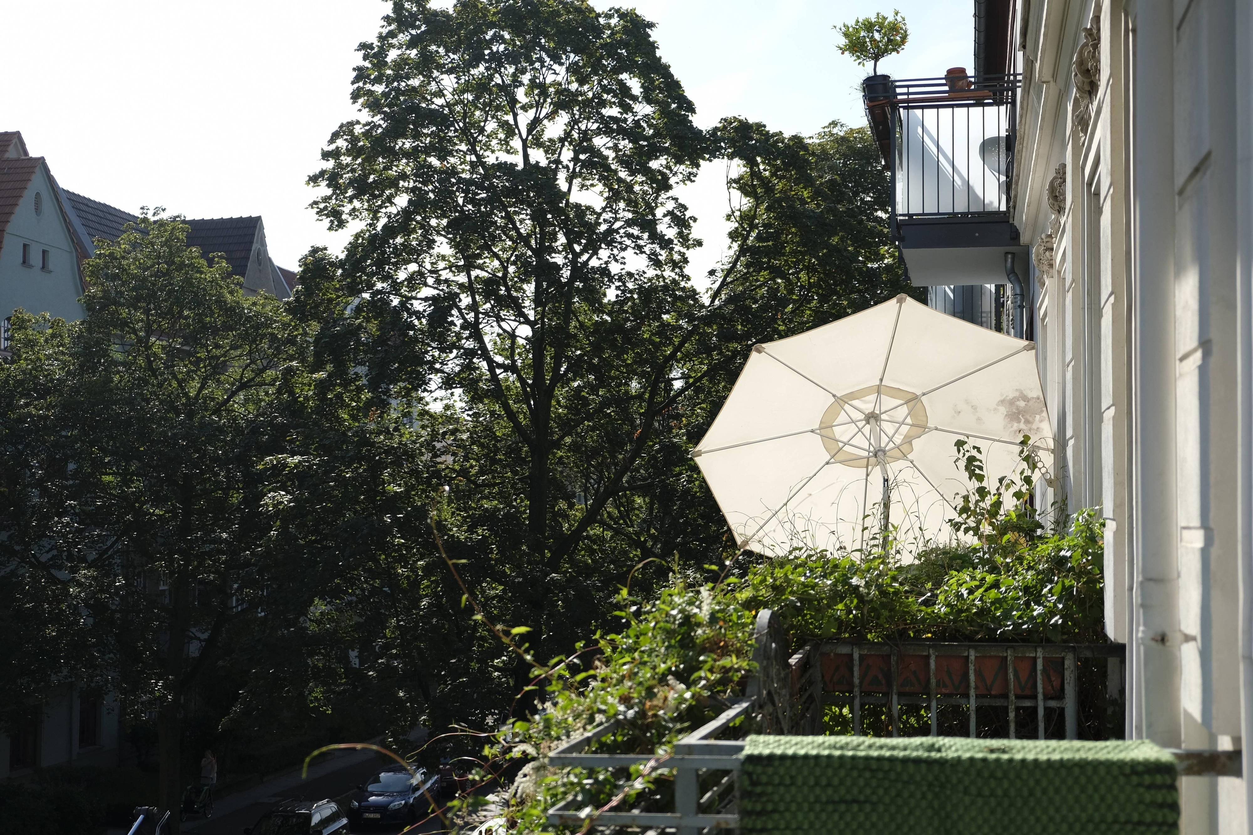 Ein Sonnenschirm ist auf einem Balkon befestigt.