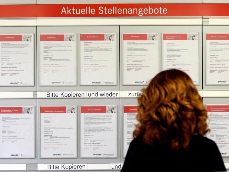 Eine Frau betrachtet in einer Arbeitsagentur aktuelle Stellenangebote. Foto: Ralf Hirschberger / Illustration