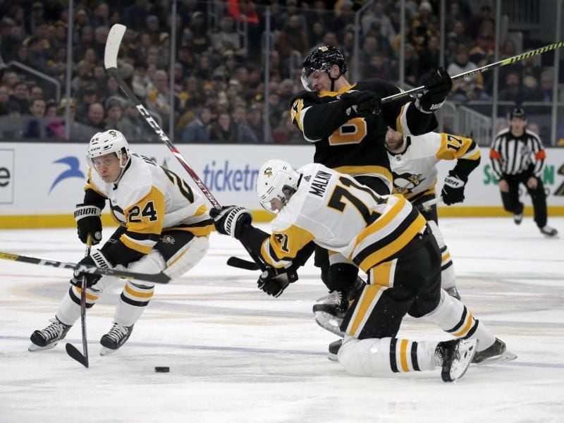 Dominik Kahun (l) von den Pittsburgh Penguins und sein Teamkollege Evgeni Malkin (vorn/71) in Aktion gegen Torey Krug (M) von den Boston Bruins. Foto: Mary Schwalm/AP/dpa