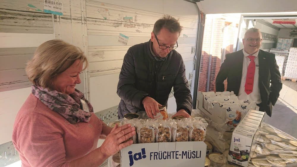 Marlies Röbbeling, Holger Franke und Helge Malerz schauen sich die gespendeten Lebensmittel an