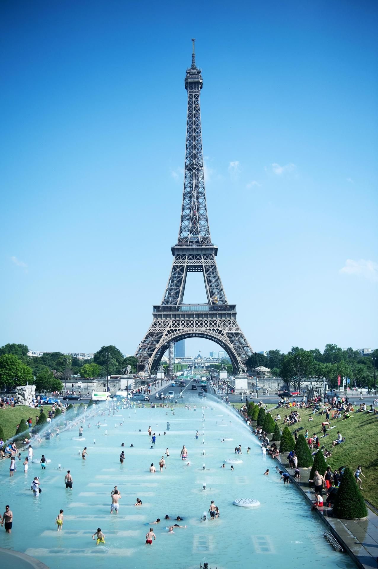 Zahlreiche Menschen kühlen sich in Paris vor dem Eiffelturm in den Brunnen am Trocadero ab.