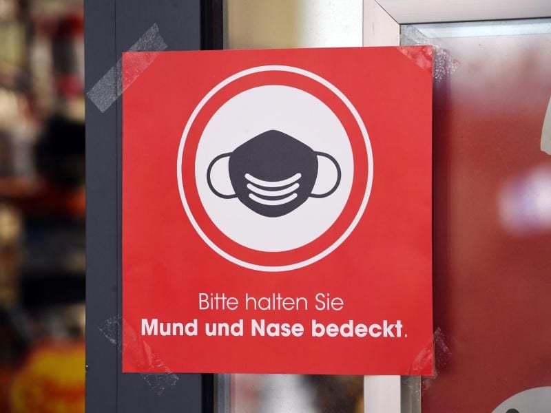 Ein Schild mit dem Schriftzug „Bitte halten Sie Mund und Nase bedeckt.”. Foto: Stefan Sauer/dpa-Zentralbild/dpa/Archivbild