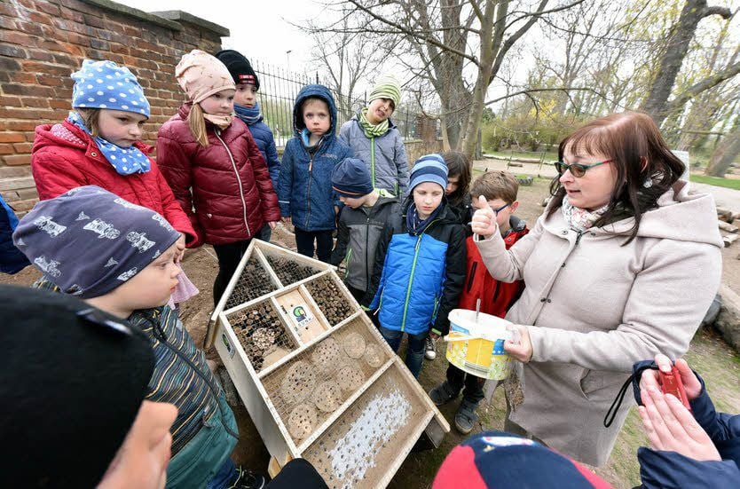 Hortleiterin Nadine Rockstroh-Thurm und die Kinder stellen das Insektenhotel auf.