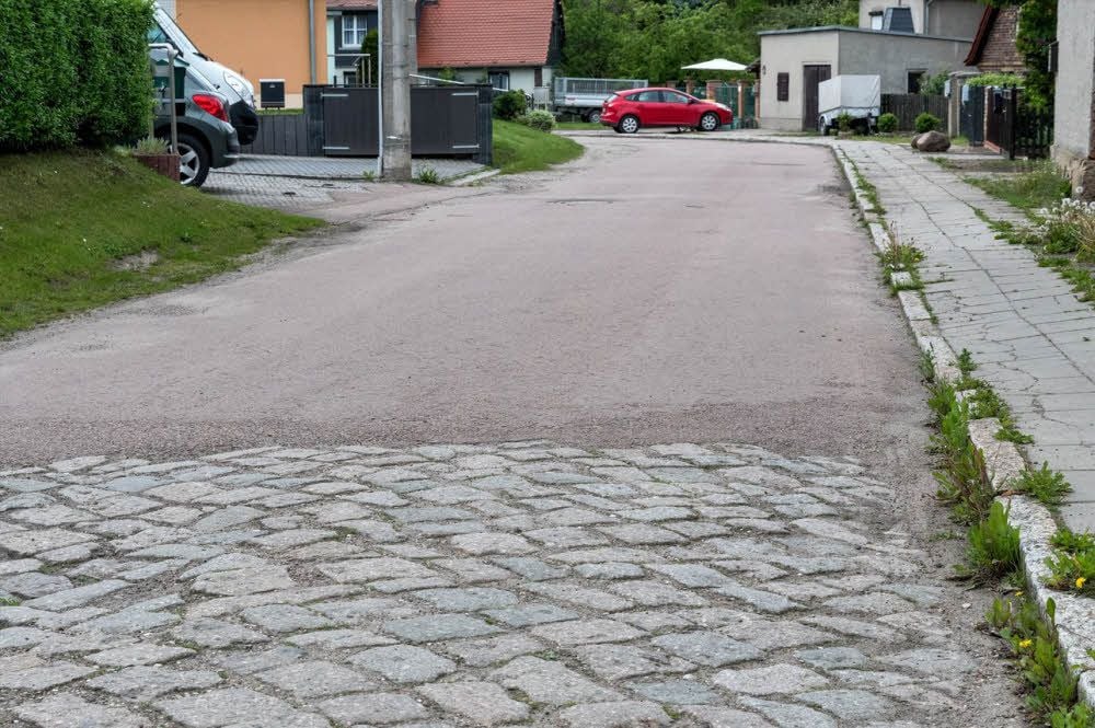 Die Teuditzer Straße in Tollwitz besteht zum Teil noch aus Kopfsteinpflaster, während ein anderer Teil bereits asphaltiert ist.