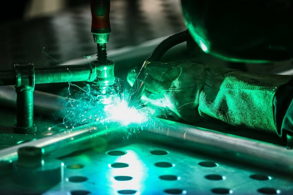 Ein Mitarbeiter schweißt Aluminiumrohre zusammen. Aus ihnen wird ein Geländer.
