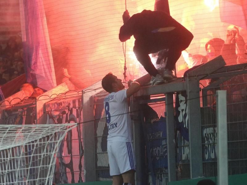 HSV-Profi Pierre-Lewis Holtby versucht die Hamburger Fans davon abzubringen, Pyrotechnik zu zünden. Foto: Thomas Frey