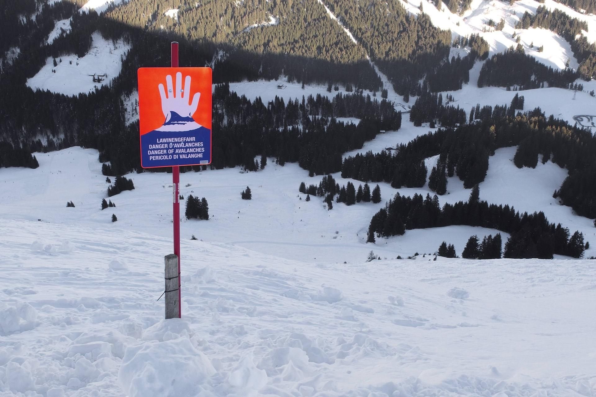 Ein Schild in den Alpen das vor Lawinen warnt.