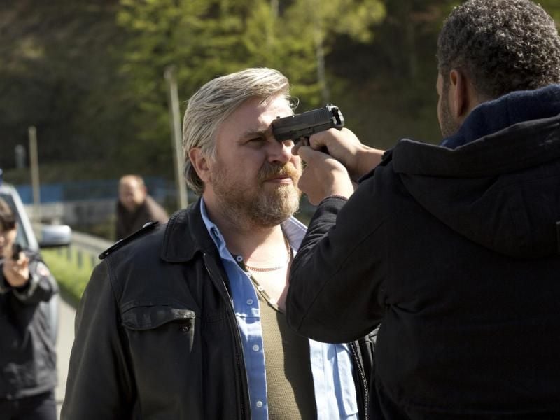 Frank Koops (Aljoscha Stadelmann, M.) wird von einem Mann mit einer Waffe bedroht. Foto: Volker Roloff/ARD Degeto
