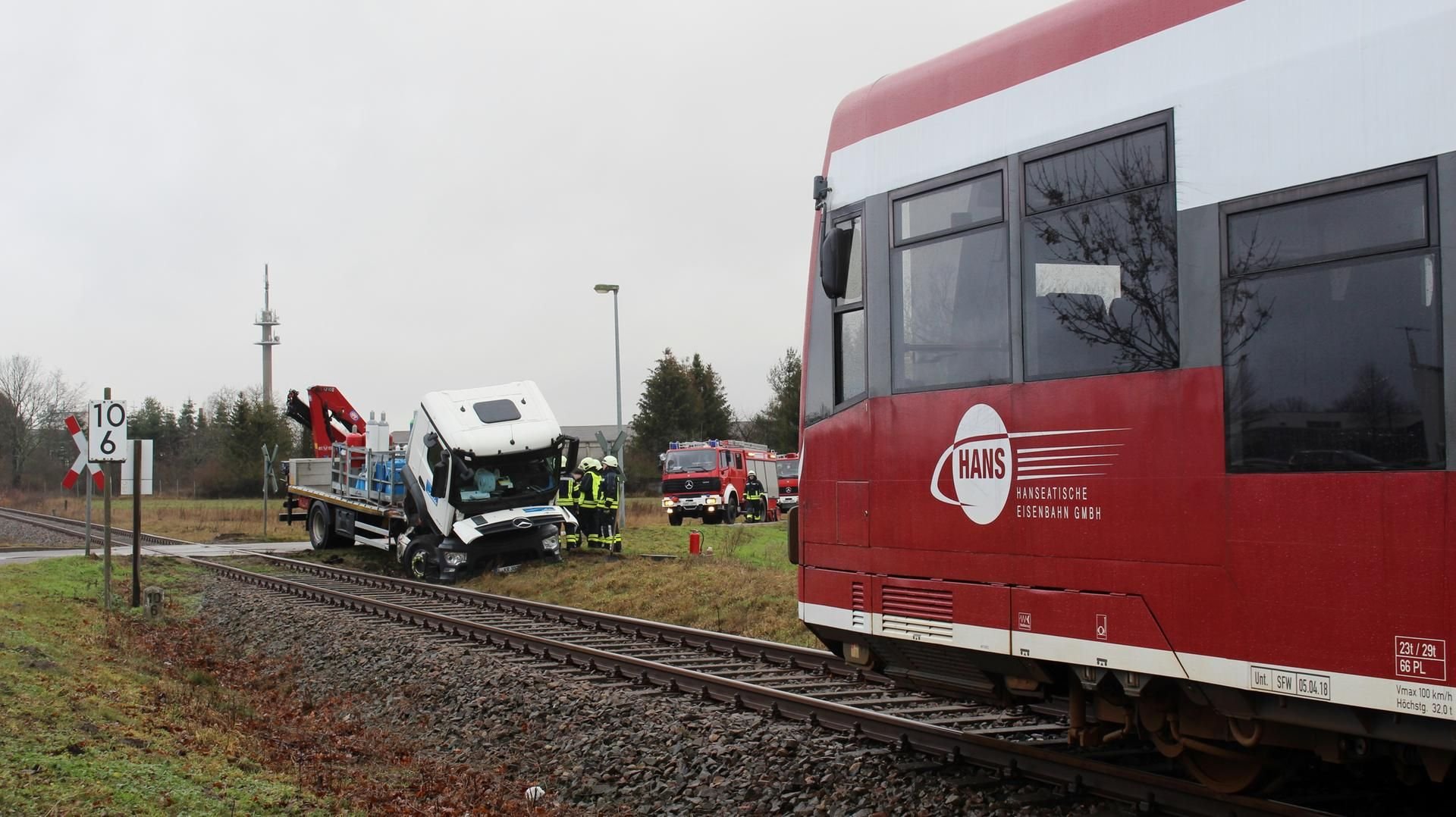 Zwei Verletzte in Kyritz: Feuerwehrleute stehen an einer Bahnstrecke neben einem beschädigten Lastwagen.