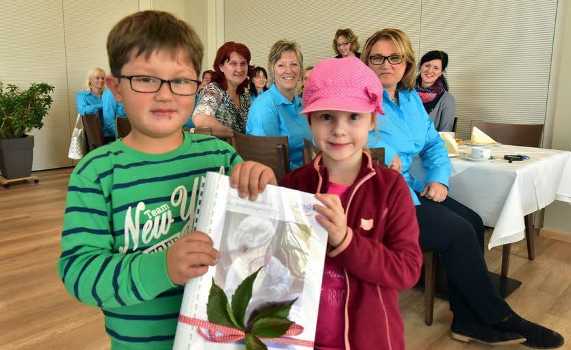Vincent Böttger und Charlotte Adomeit übergeben das Qualitätshandbuch ihren Erziehern. Auch die Kinder haben daran mitgearbeitet.