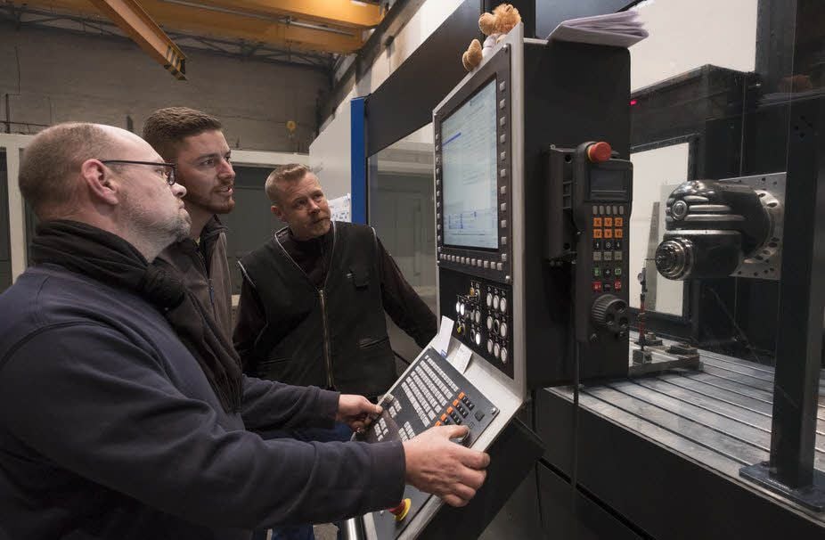 Zusammen mit Servicetechniker Dirk Löcker richten Martin Jänichen und Mike Goronzi (v.l.) die nagelneue Maschine ein.