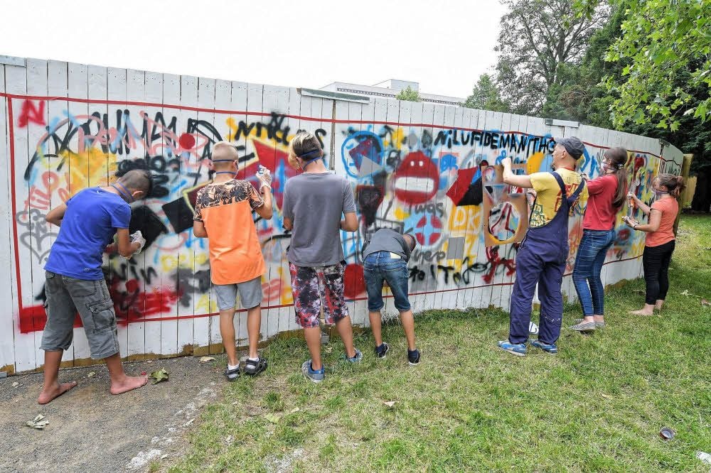 Mädchen und Jungen aus Gymnasien, Sekundarschulen und Jugendklubs testen am Anfang ihre Sprayerkünste an einer Probierwand.