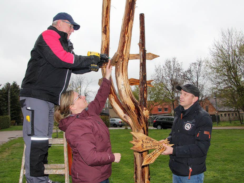 Kurt Kuchinke (v. li.) Jacqueline Binnemann und Ivo Fräsdorf bringen die Schilder am Wegweiser auf dem Spielplatz in Cölbigk an.