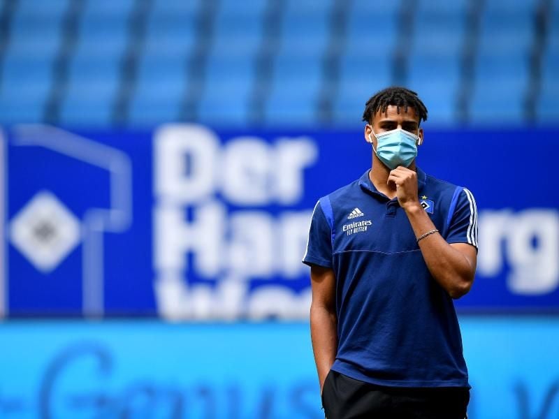 Jan Gyamerah vom Hamburger SV steht mit Mundschutz auf dem Platz. Foto: Stuart Franklin/Getty Images Europe/Pool/dpa/Archivbild