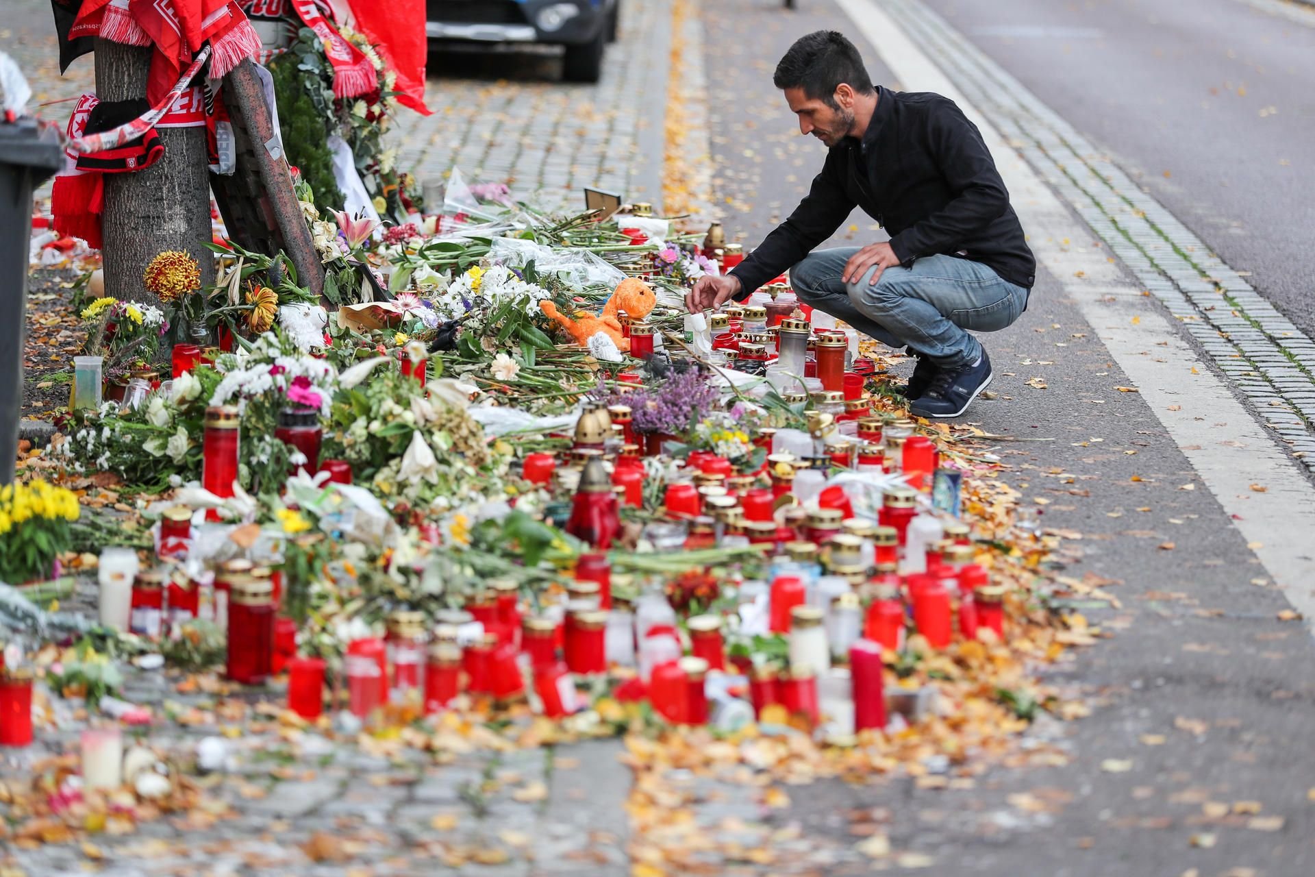 Izzet Cagac, Betreiber des Kiez-Döners, hockt vor dem Meer aus Kerzen und Blumen vor seinem Imbiss.
