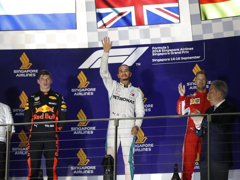 In Singapur feiert Lewis Hamilton (M) zwischen dem Max Verstappen (l) auf Rang zwei und Sebastian Vettel seinen Sieg. Foto: Vincent Thian/AP