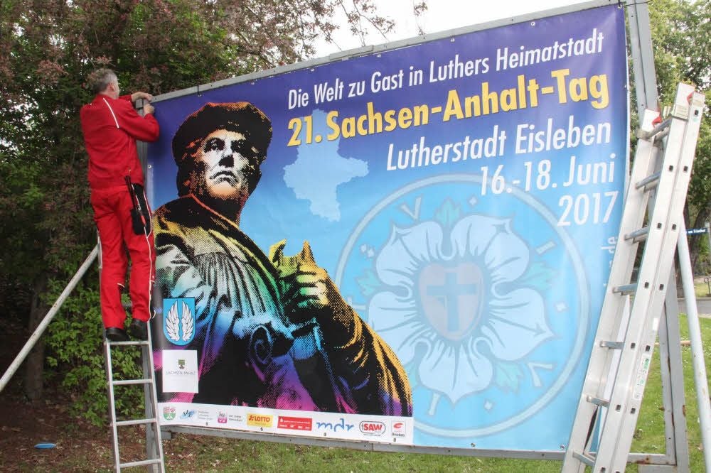 Ein Mitarbeiter der Firma Bluhm befestigt eines der Plakate.