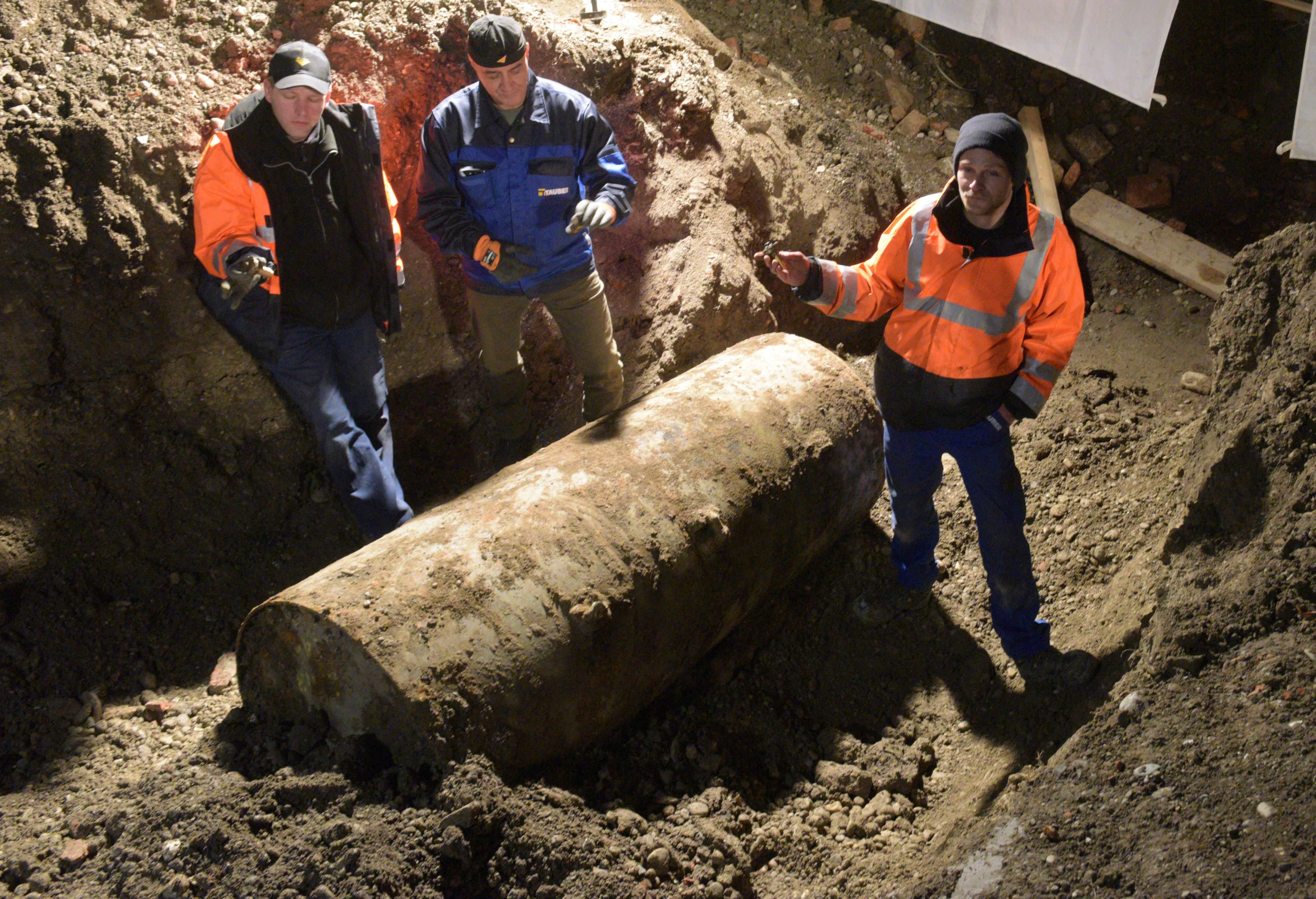 Nach der geglückten Entschärfung einer Fliegerbombe stehen die Sprengmeister neben der Bombe.