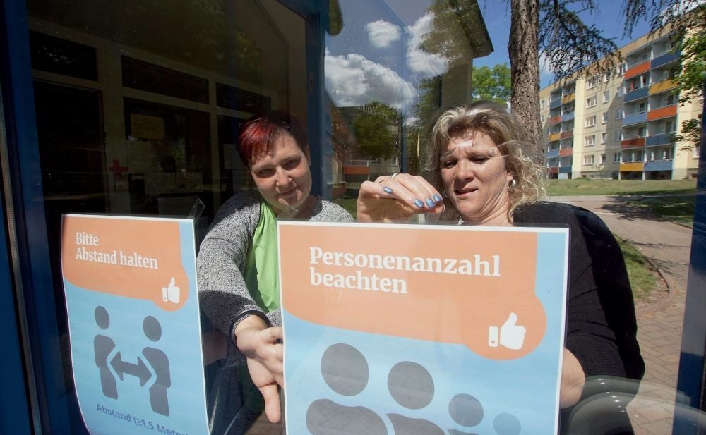 Kita-Leiterin Susan Stemmler (re.) und Hortleiterin Peggy Kasimir befestigen die Hinweise für die Wiedereröffnung.