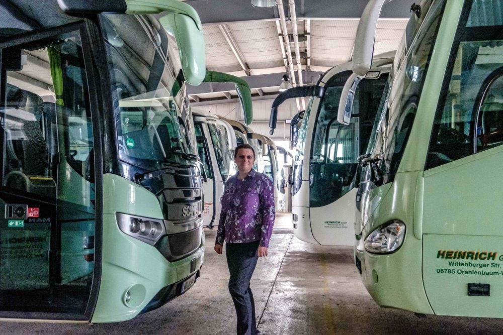 Geschäftsführerin Antje Heinrich steht in der Halle zwischen den Bussen des Oranienbaumer Unternehmens, die derzeit nicht rollen.