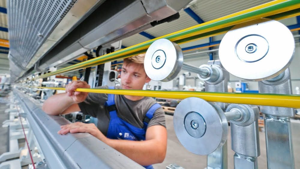 Lucas Schneider kontrolliert an der neu gebauten Maschine die fertigen Kabel.