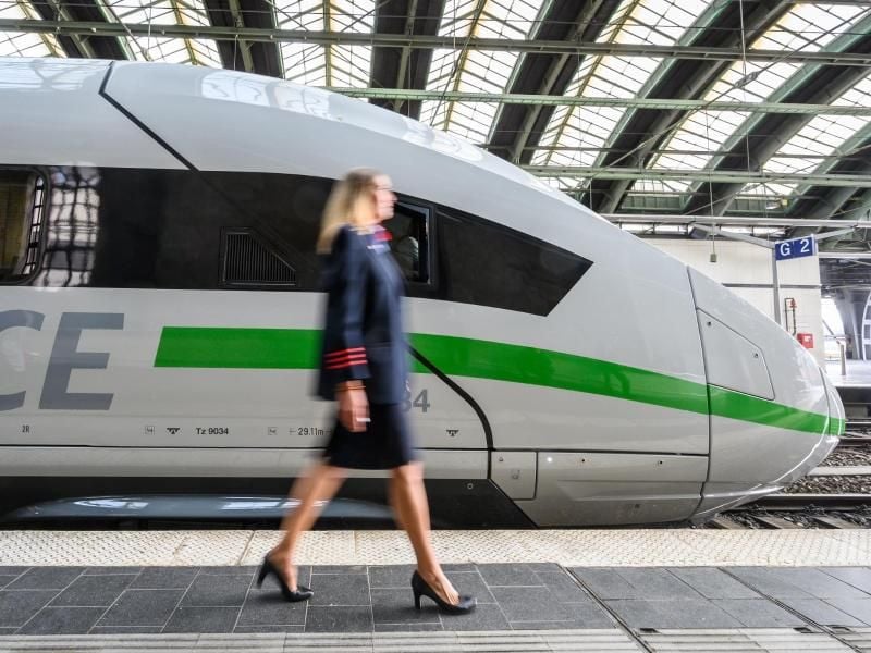 Eine Mitarbeiterin der Bahn geht an einem ICE mit dem neuen Design vorbei. Foto: Christophe Gateau