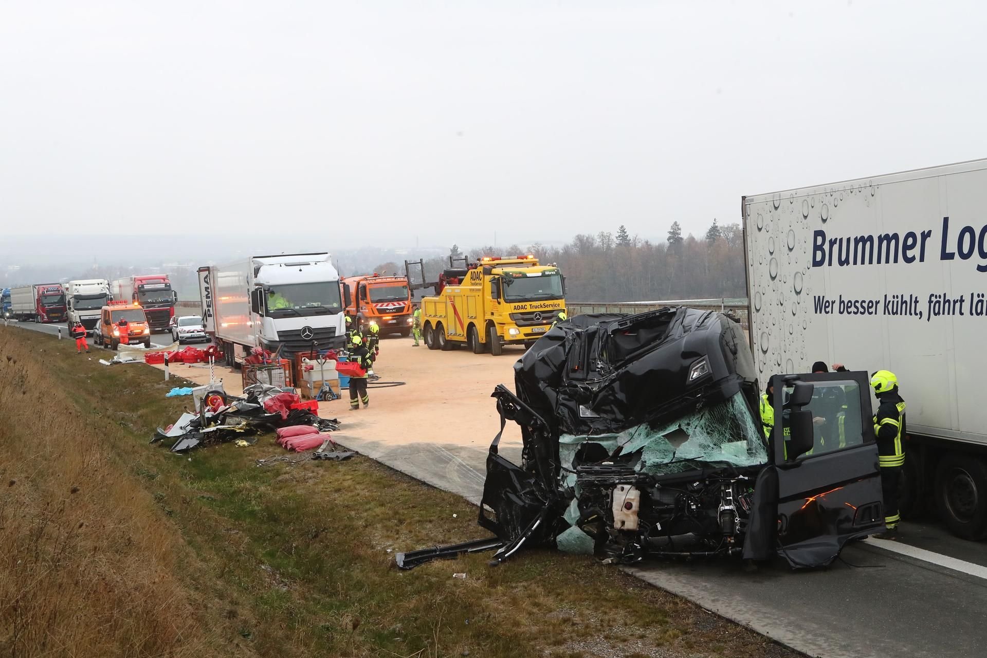 Triptis: Feuerwehrleute stehen am Dienstag vor dem völlig zerstörten Fahrerhaus eines Lkw auf der Autobahn 9 bei Triptis.