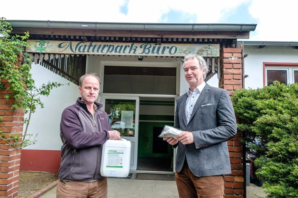 Chemieparkchef Patrice Heine (r.) übergibt Axel Mitzka, dem Vorsitzenden des Vereins Dübener Heide, Desinfektionsmittel und Masken.