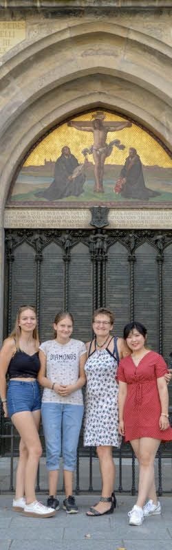 Anna Wang mit ihrer Gastfamilie Theres Hellmann, Amelie Hellmann und Doreen Hellmann vor der Thesentür der Schlosskirche in Wittenberg.