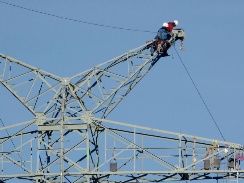 Monteure arbeiten an einem Strommast der Westküstenleitung. Foto: Carsten Rehder/Archivbild