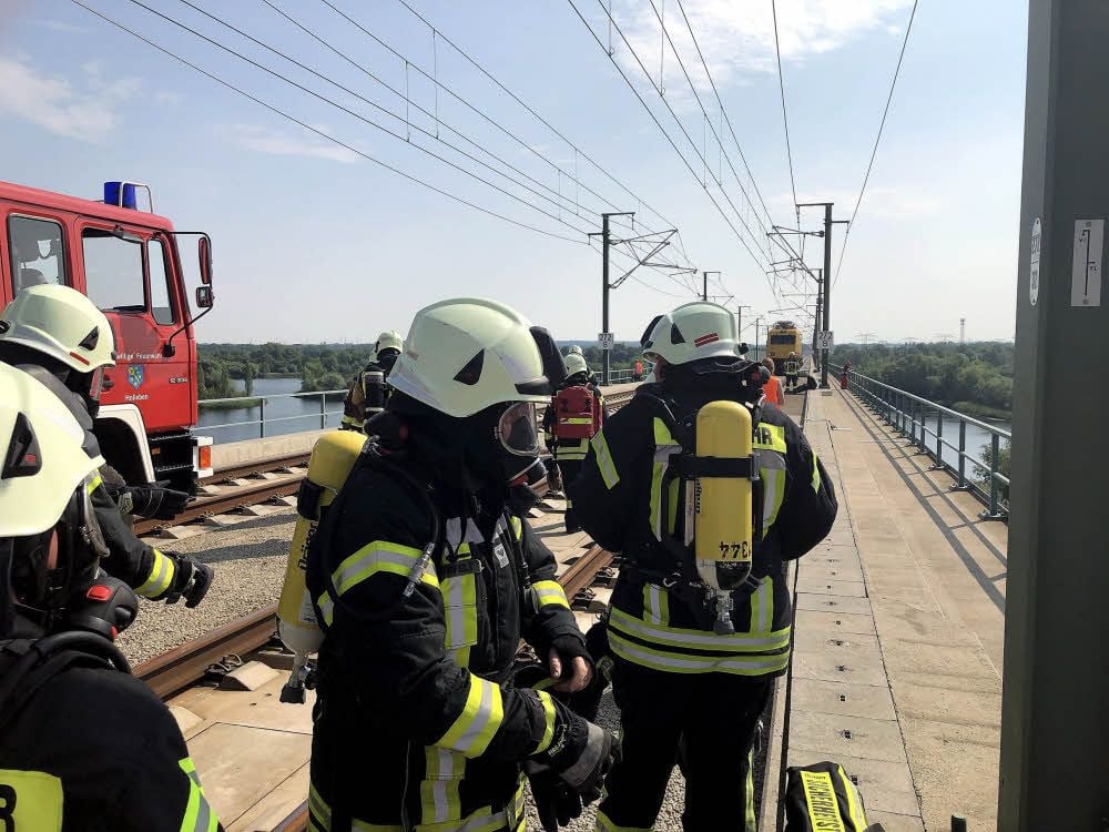 Das erste Feuerwehrfahrzeug ist auf die ICE-Brücke gefahren und die Kameraden legen ihren Atemschutz an.