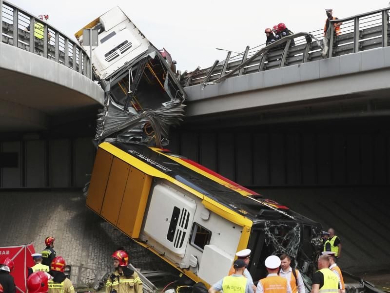 Einsatzkräfte arbeiten an der Unfallstelle. Mindestens ein Mensch ist bei dem Absturz des Linienbusses ums Leben gekommen. Foto: Czarek Sokolowski/AP/dpa