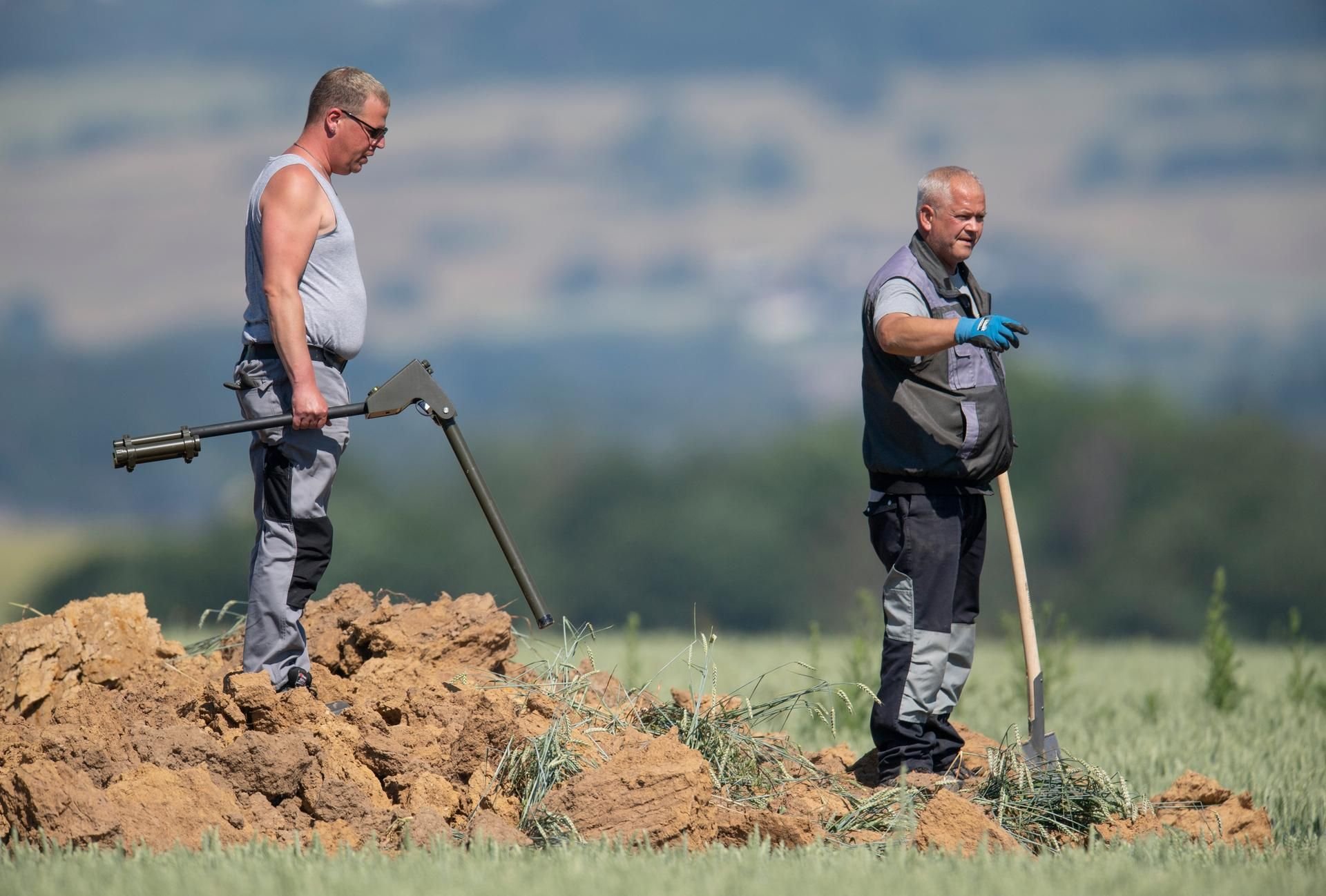 Mit Metallsonden und Spaten untersuchen Experten des Kampfmittelräumdienstes einen riesigen Krater.