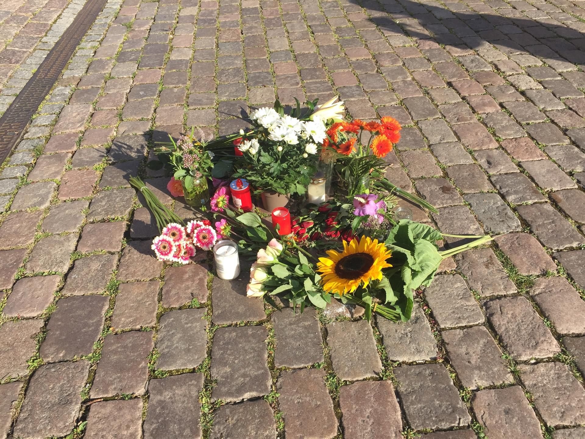 Blumen liegen auf dem Platz vor dem Kieler Rathaus, wo am Montag eine Frau von einem Fahnenmast erschlagen wurde.