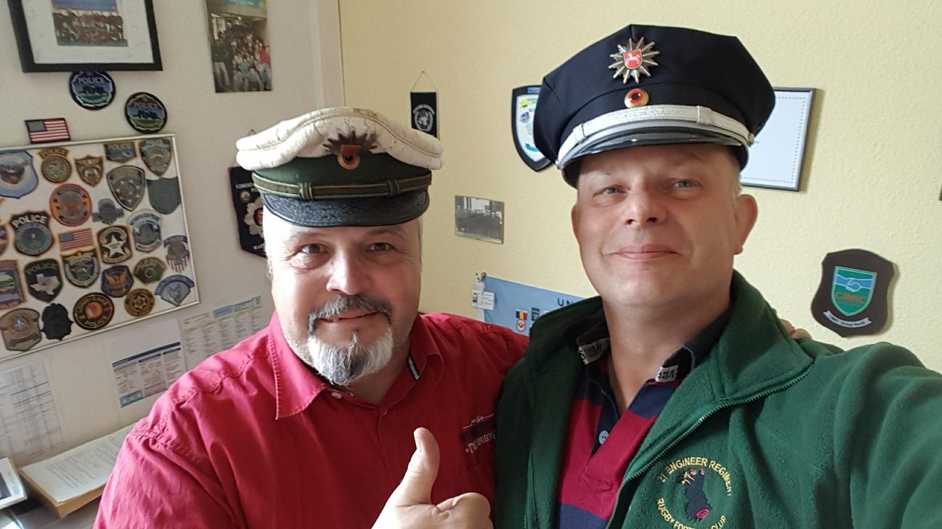 Polizeioberkommissar Gabor Balint (l) - mit einer vor 37 Jahren gestohlenen Polizeimütze - und der Überbringer Graham Morley machen ein gemeinsames Foto.