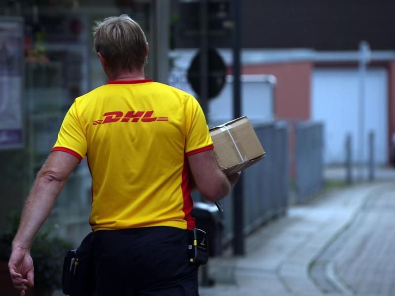 Ein DHL-Mitarbeiter liefert ein Paket aus. Foto: picture alliance / dpa