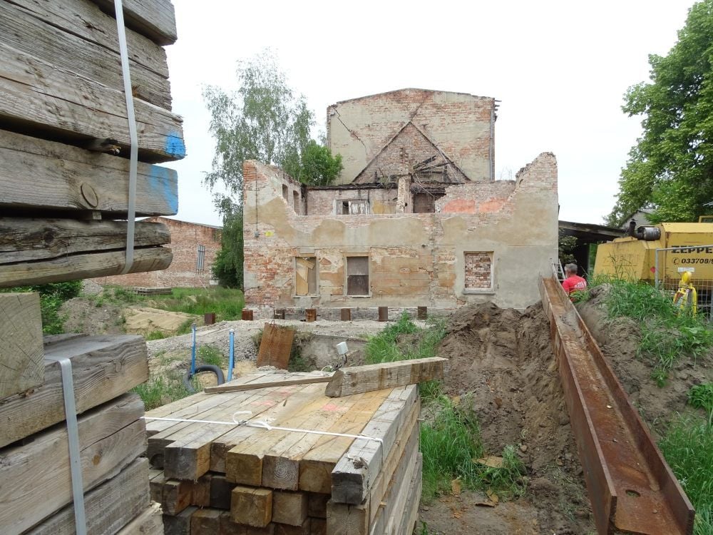 Blick auf die Mühle. Unmittelbar vor der Giebelwand ist die Baugrube. Sieben Pfeiler sichern das Fundament.