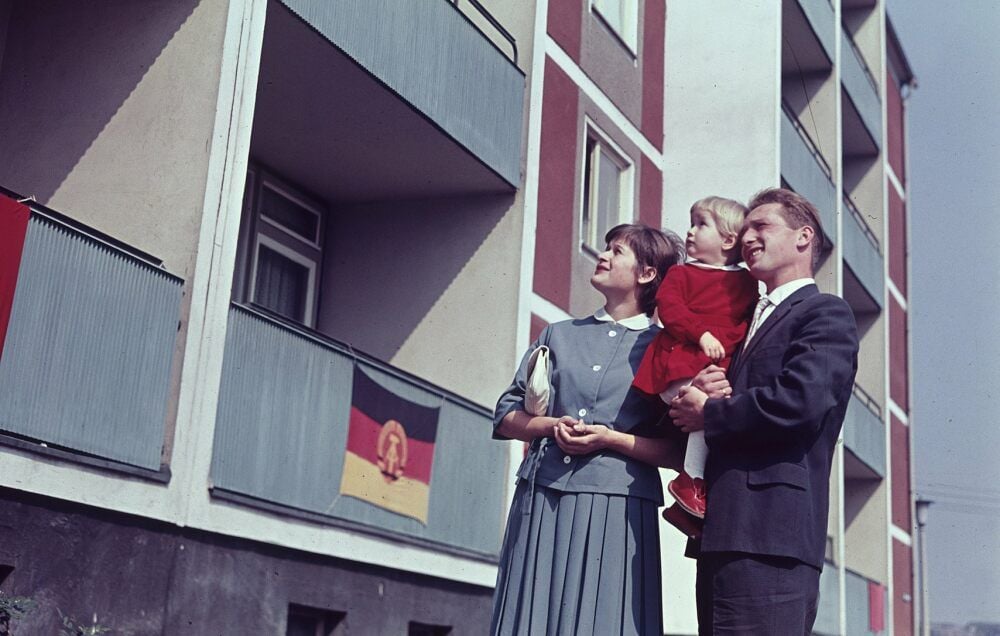In Erwartung von Fernheizung und fließend Warmwasser: Junge Familie vor Plattenbau in Ost-Berlin 1963.