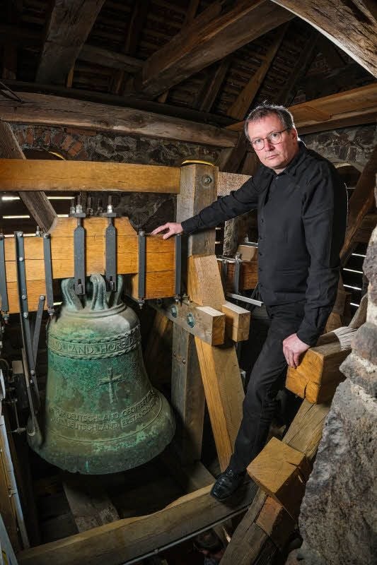 Pfarrer Albrecht Henning und die Glocke des Anstoßes. Das aufgeprägte Hakenkreuz ist aus dieser Perspektive nicht zu sehen. Die MZ hat bewusst darauf verzichtet, es zu zeigen, um keine NS-Symbole zu verbreiten.