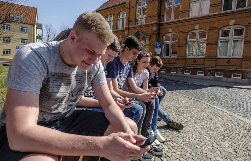 Digitaler Alltag. Schüler der 11. Klasse lernen in der Pause mit dem Handy, hier vor dem Gymnasium in Gräfenhainichen.
