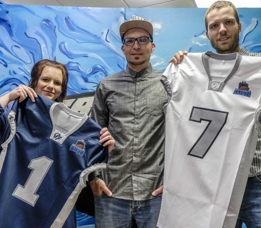 Die Hobby-Designerin Sophie Hildebrandt, der Fresh-Stylez-Shop-Geschäftsführer Frank Jedlitschka und Saints-Chef Christian Weise präsentieren die Trikots der American Footballer.