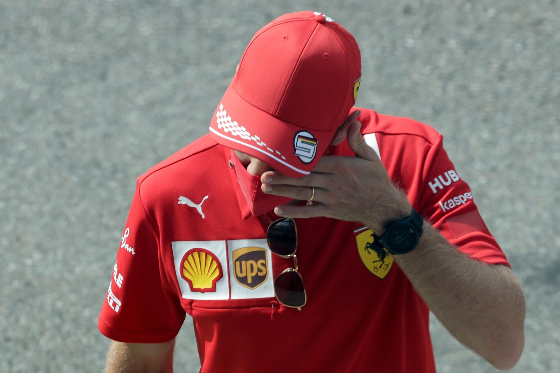 Sebastian Vettel vom Team Scuderia Ferrari steht mit einer roten Maske an der Rennstrecke.