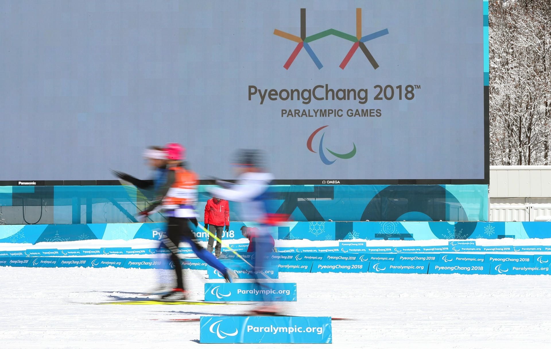 Athleten laufen vor dem olympischen Logo.