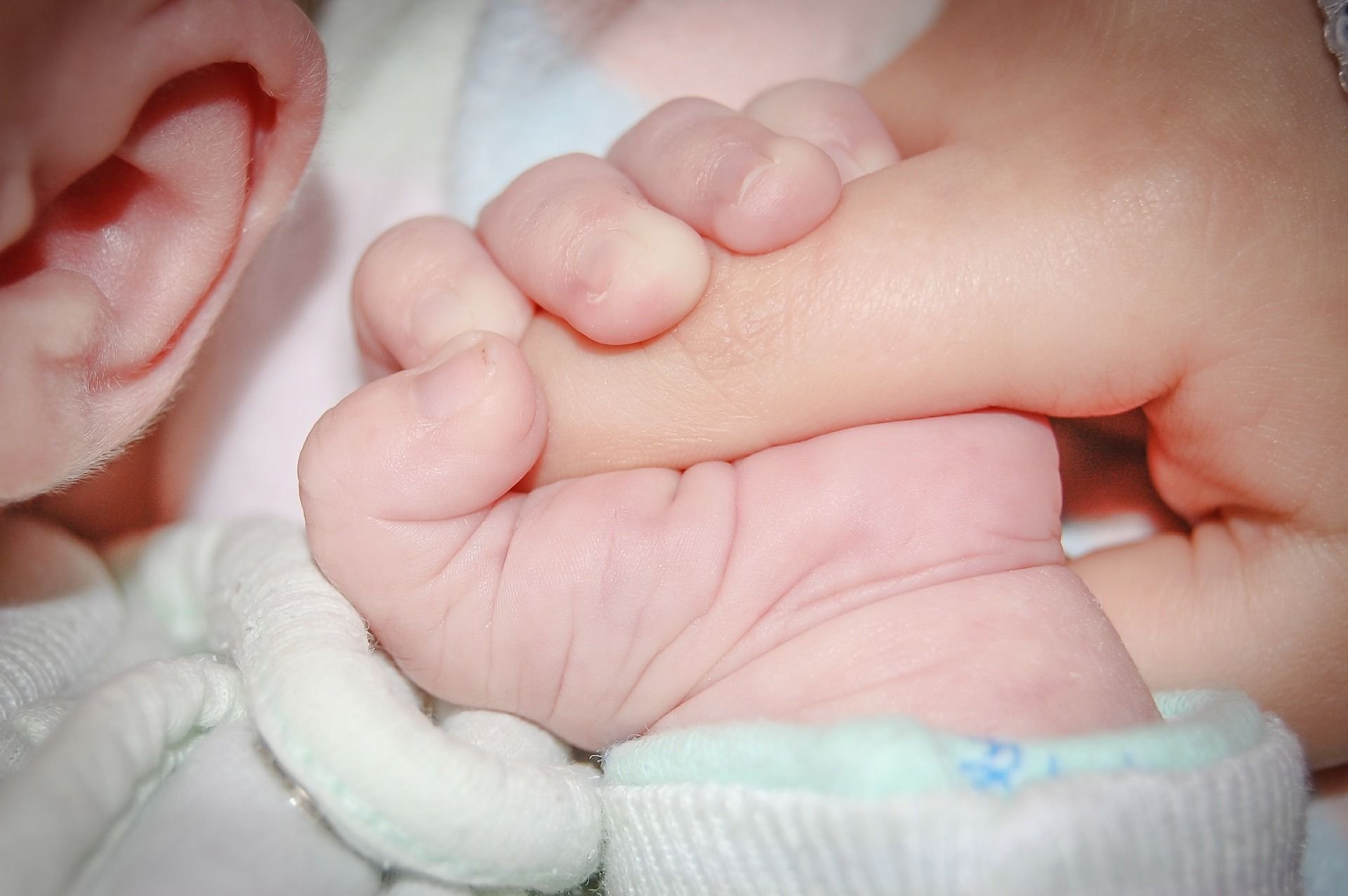 Ein Baby hält einen Finger fest.