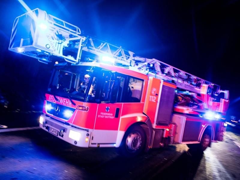 Ein Drehleiterwagen der Feuerwehr fährt mit Blaulicht an einer Unfallstelle vorbei. Foto: Marcel Kusch/dpa/Illustration
