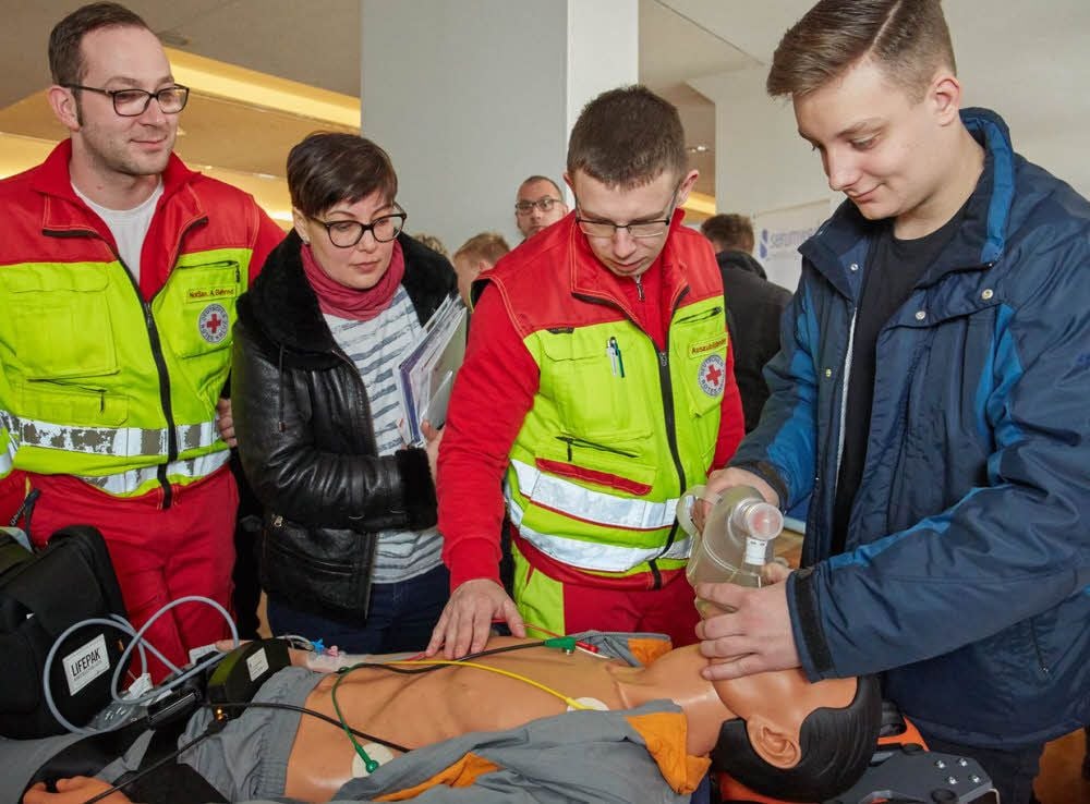 Davis Gubbels (re.) und seine Mutter Tatjana Sokhauka informerien sich bei Andreas Behrnd (li.) und David Gerstenberger (2. v. re.) vom DRK über den Beruf des Rettungssanitäters.