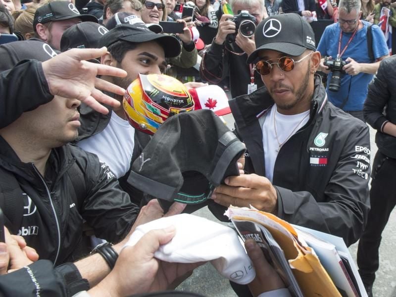 Der Brite Lewis Hamilton (r) gibt vor den Vorbereitungen in Montréal Autogramme. Foto: Ryan Remiorz/The Canadian Press