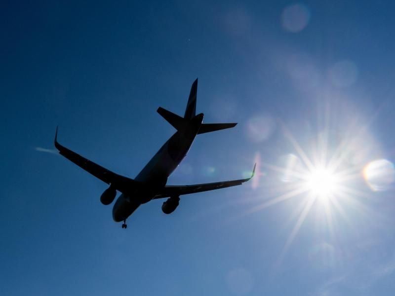 Ein Flugzeug fliegt am blauen Himmel vorbei. Foto: Robert Michael/zb/dpa/Symbolbild
