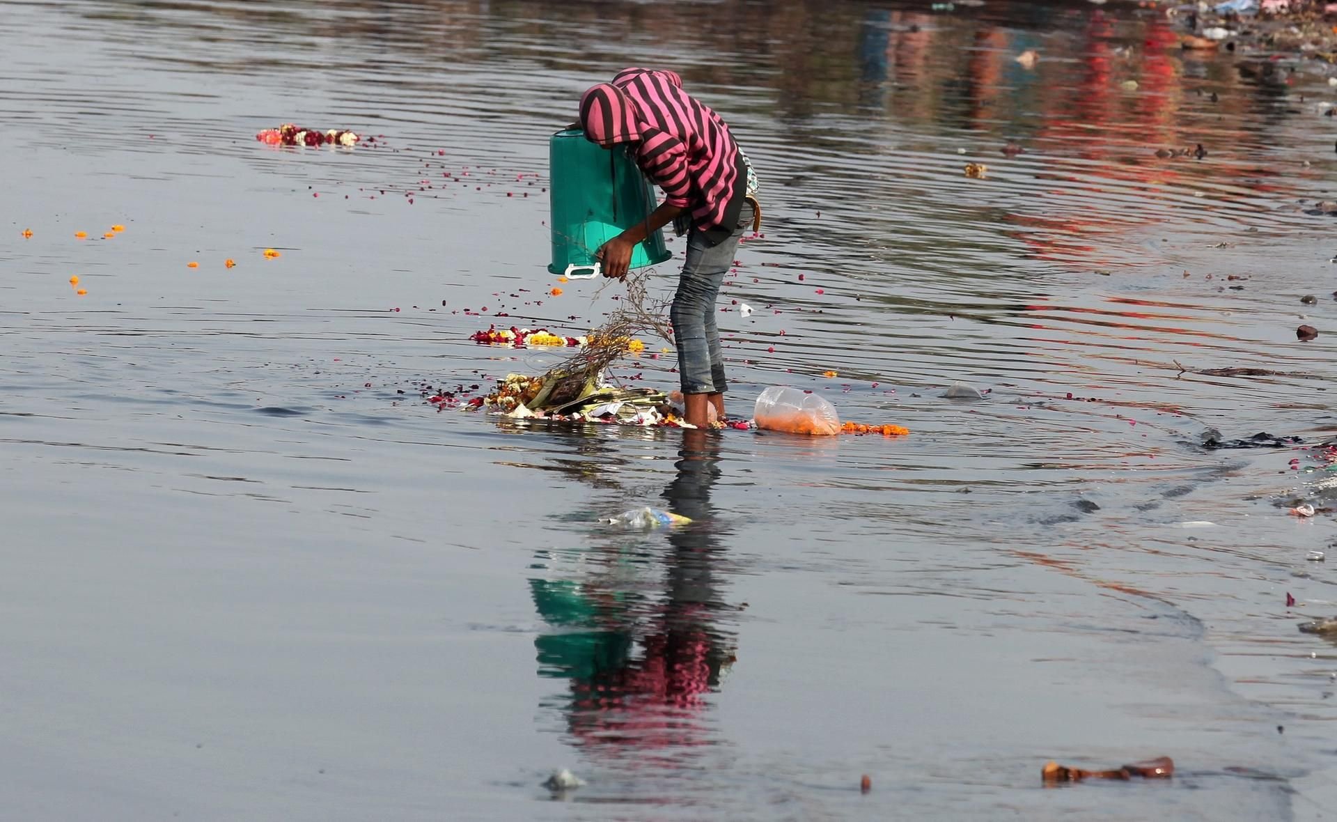 Ein Junge schüttet Abfall in einen indischen Fluss. Viele Gewässer dort sind auch mit Rückständen aus der Pharmaindustrie belastet.